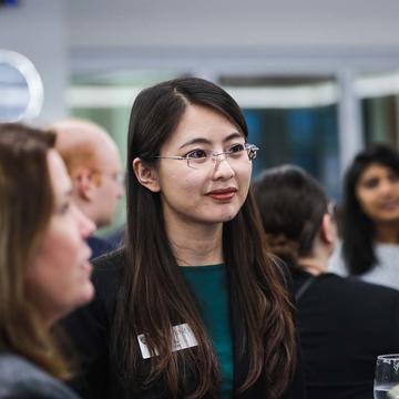 Female student in teal shirt and glasses networking