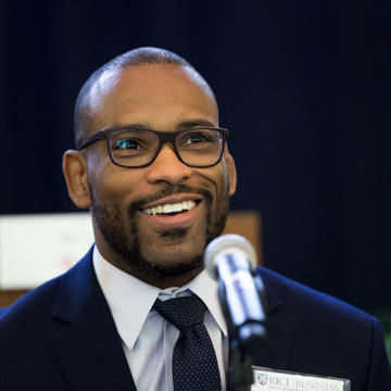 male student with glasses smiling into microphone