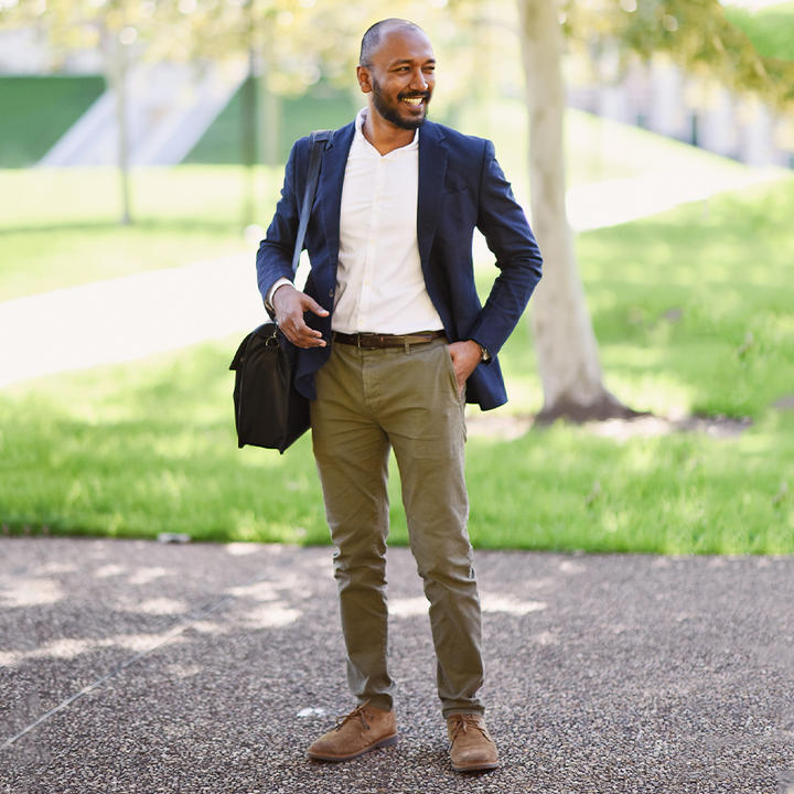 Male student with messenger bag standing outside