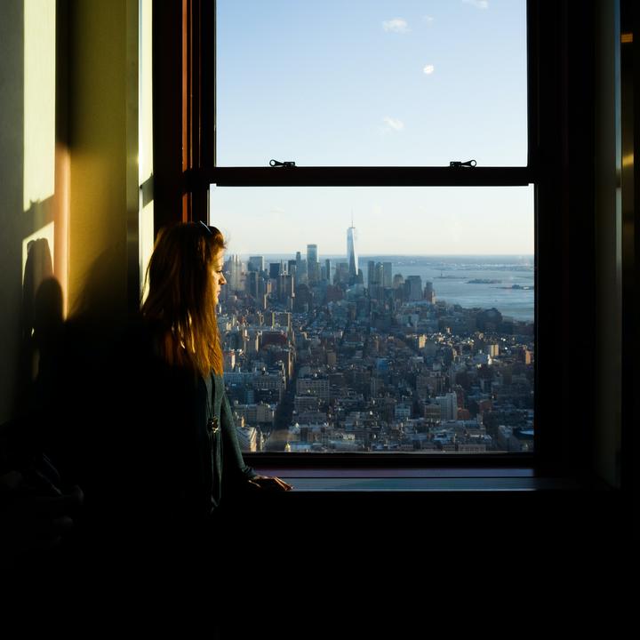 Hardship presents opportunity - woman looking out window over city