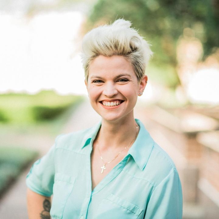 Young woman with short blonde hair smiling at camera