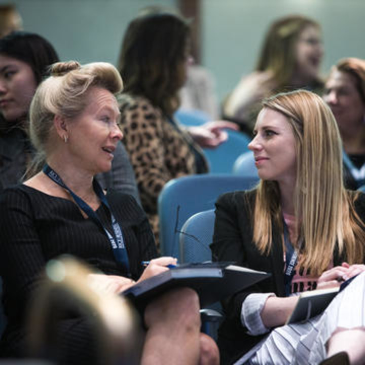 Female Rice MBA student networking with a woman in Shell Auditorium