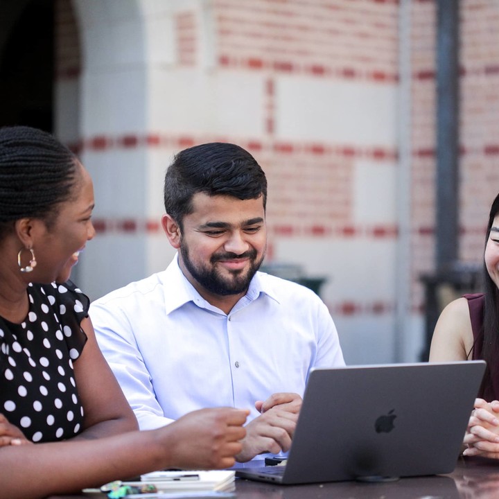 MBA students sitting outside McNair Hall with their laptops