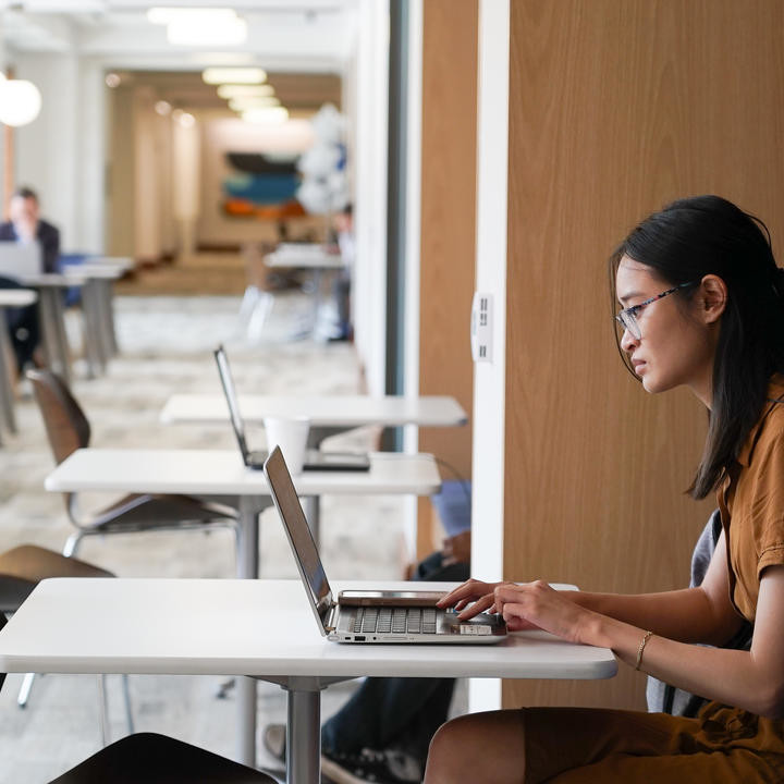 girl on laptop sitting in hallway of business school